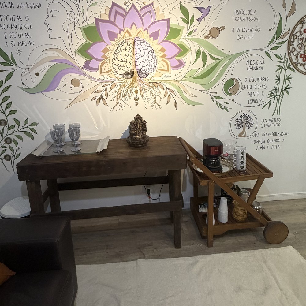 Balcão de madeira do consultório com um buda, velas, plantas e a arte da árvore-mão emoldurada.